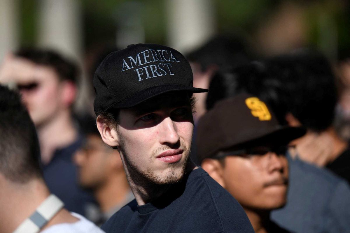 A college student wearing an "America First" hat 