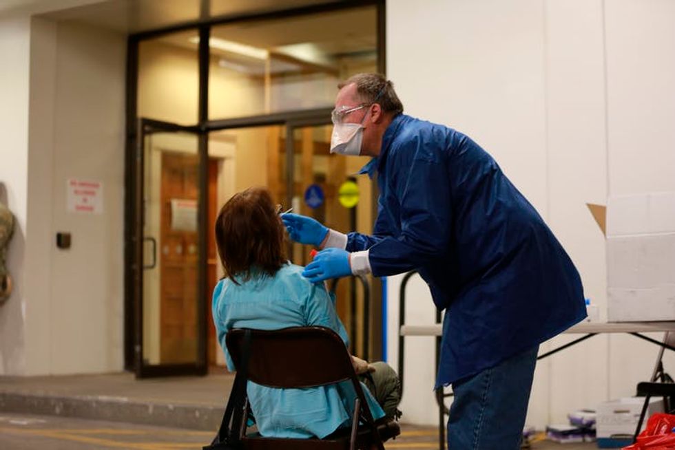 A doctor using a nasal swab to test a state senator of New Mexico.