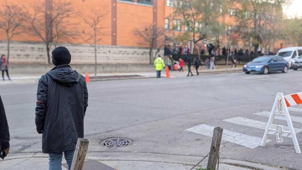 A volunteer with Rogers Park School Patrols watches a school 