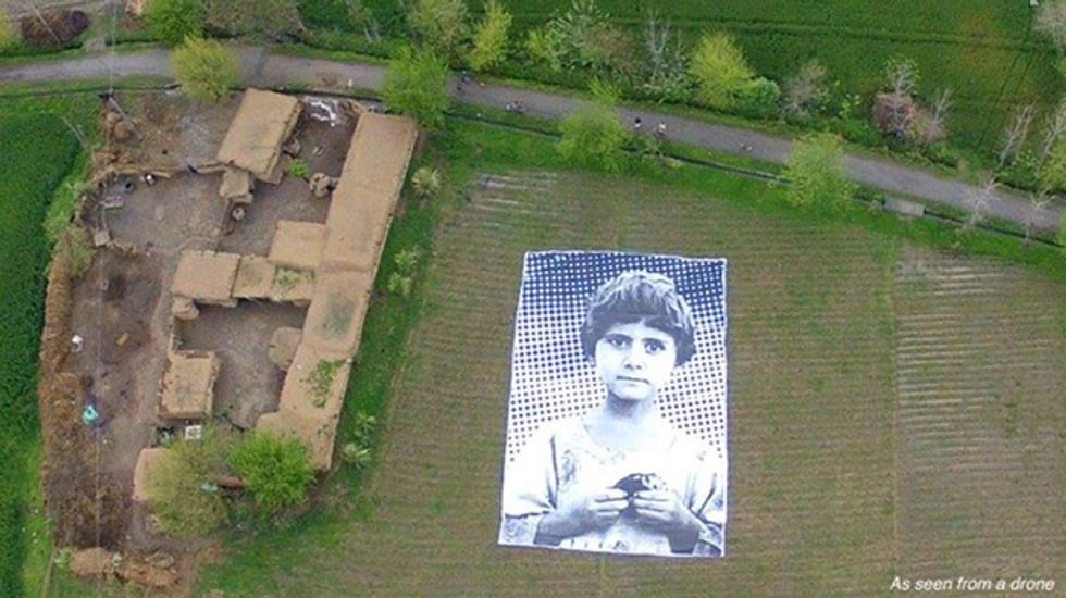 Artists install massive poster of child's face in Pakistan field to shame drone operators