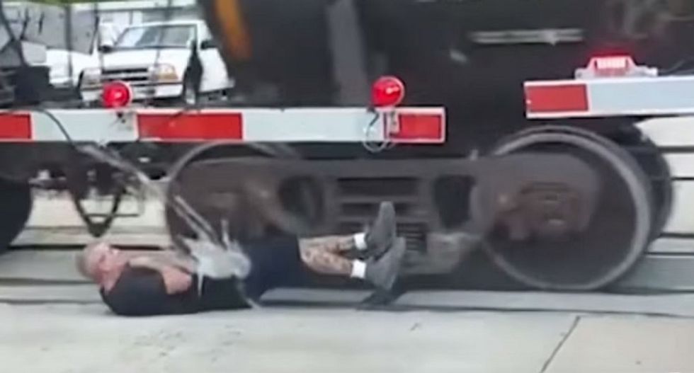WATCH: Man defies death and rolls through wheels of moving freight train