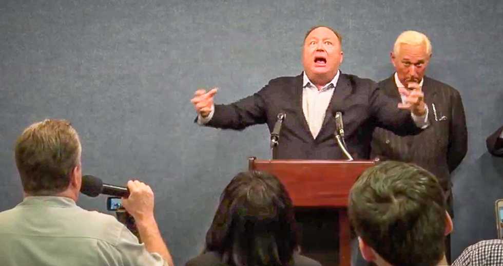 WATCH: Alex Jones goes berserk and molests the American flag when he's asked about his links to Russia