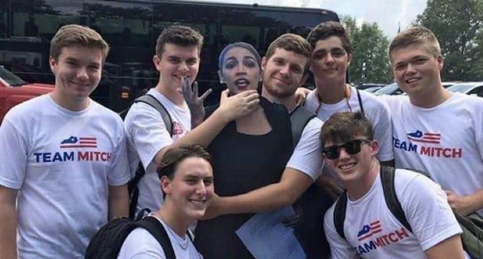 Young Mitch McConnell supporters pose for a photo strangling a cardboard cutout of AOC