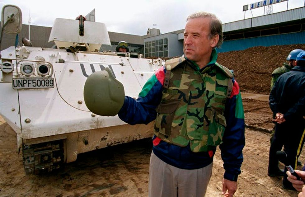 Joe Biden in Bosnia wearing camouflage and standing near a tank