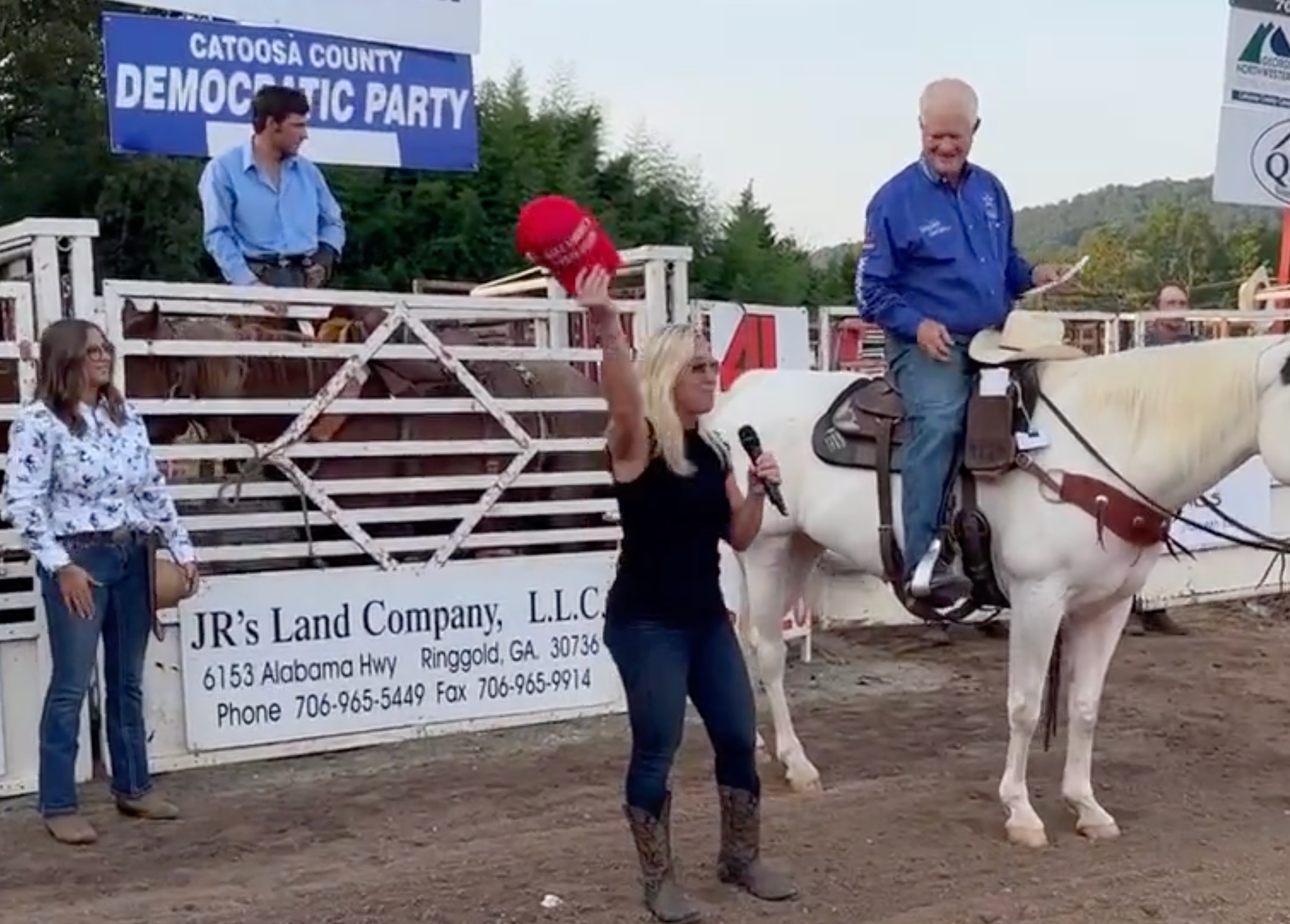 Marjorie Taylor Greene recites pledge under Democratic party sign at rodeo