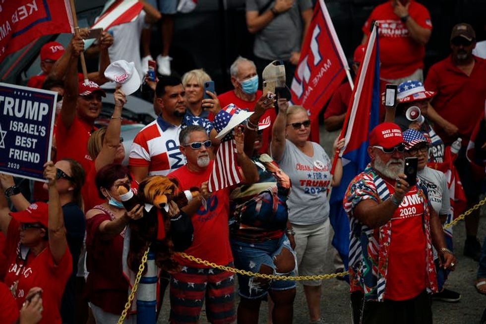Maskless Trump supporters are seen in a crowd.