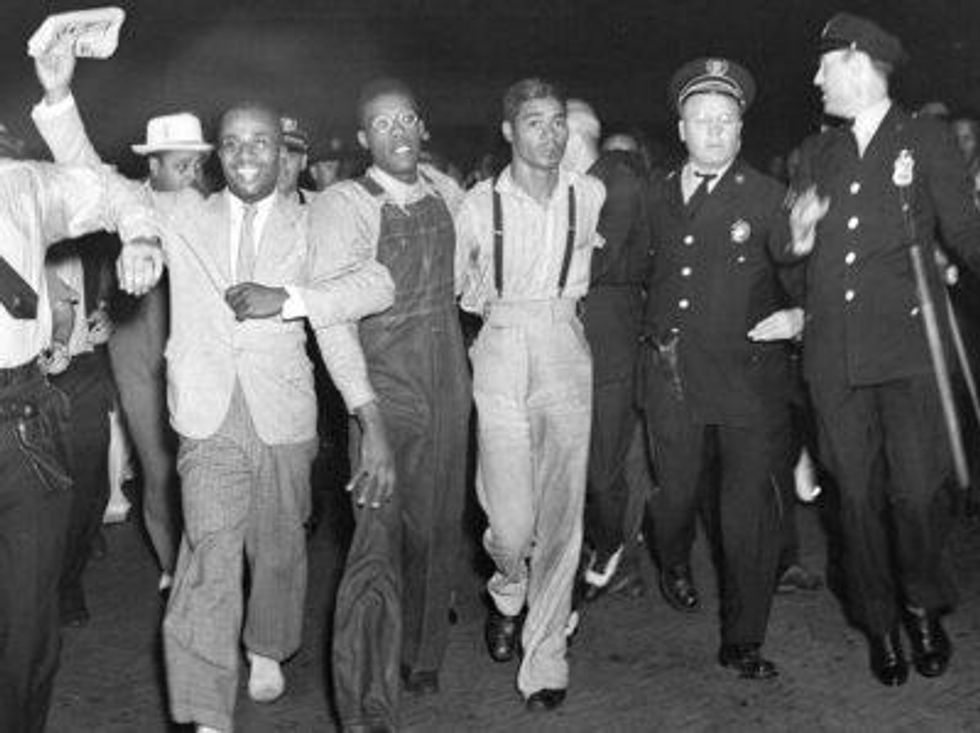 \u200bIn this July 26, 1937 file photo, police escort two of the five recently freed "Scottsboro Boys," Olen Montgomery, wearing glasses, third left, and Eugene Williams, wearing suspenders, fourth left, through the crowd greeting them upon their arrival at Penn Station in New York.